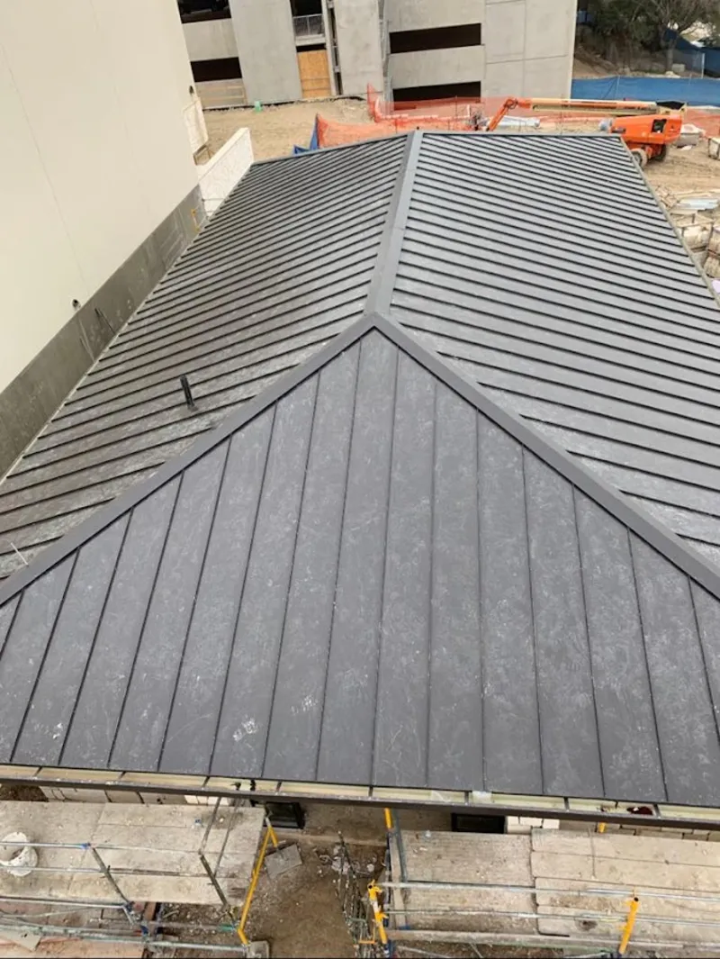 Commercial metal roof construction with crane equipment in Wayland