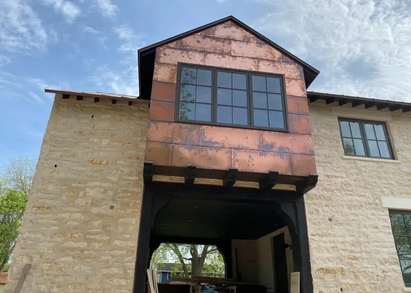 Copper metal panel facade on a stone building for Roof Repair in Wayland